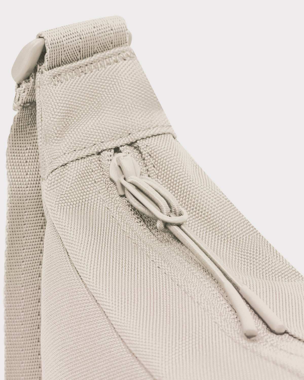 Detailansicht des Reißverschlusses und der Trageschlaufe der sandfarbenen Half Moon Bag 'Ally Small'