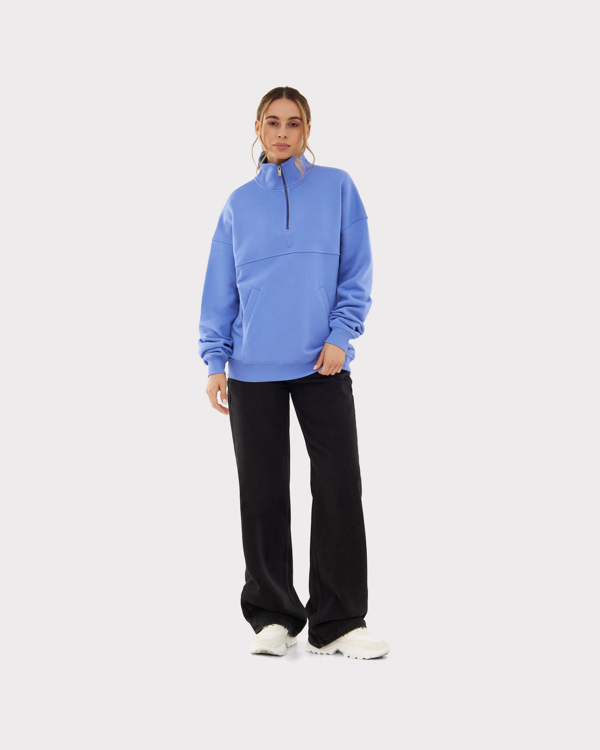 Frau trägt blauen Half-Zip-Pullover 'Cooper' von Johnny Urban mit schwarzer Hose und weißen Schuhen