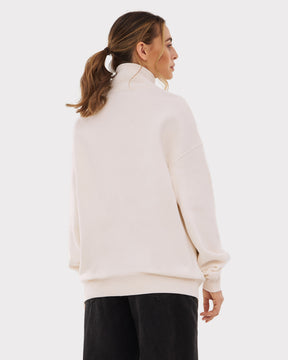 Frau von hinten in cremeweißem Half-Zip-Sweatshirt ‚Cooper‘ mit hohem Kragen und schwarzen Hosen