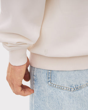 Nahaufnahme eines cremeweißen Half Zip Sweatshirts 'Cooper' mit elastischem Bündchen am Handgelenk und Saum, getragen zu hellblauen Jeans