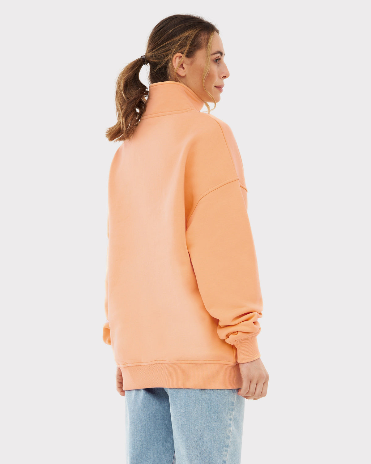 Frau trägt pfirsichfarbenen Half Zip Sweatshirt 'Cooper' von Johnny Urban, Rückansicht, dazu blaue Jeans