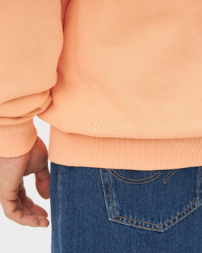 Detailansicht des saumlosen Bündchens eines pfirsichfarbenen Half Zip Sweatshirts 'Cooper' von Johnny Urban über blauen Jeans