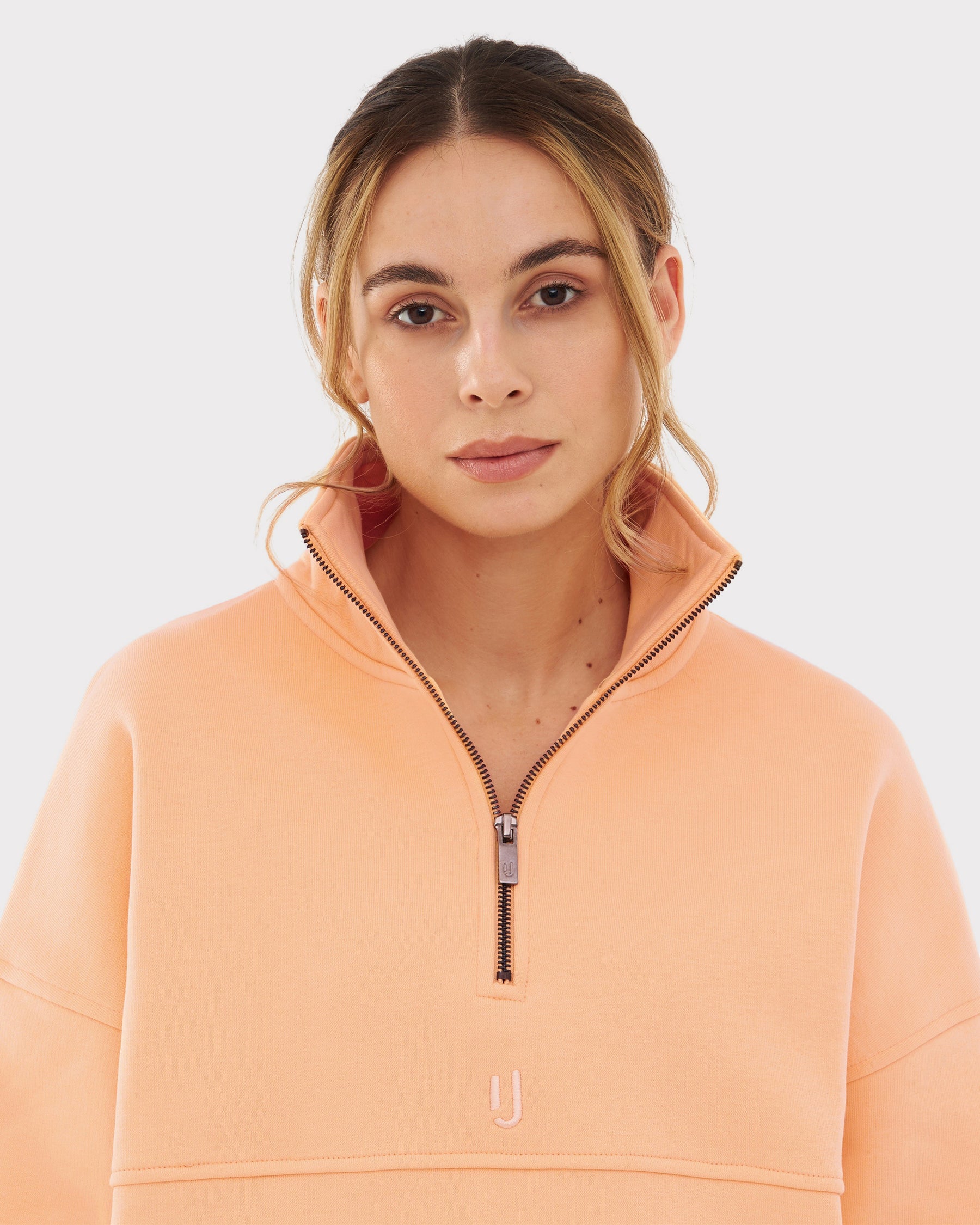 Frau trägt Half Zip Sweatshirt 'Cooper' von Johnny Urban in pfirsich, mit hohem Kragen und halbem Reißverschluss