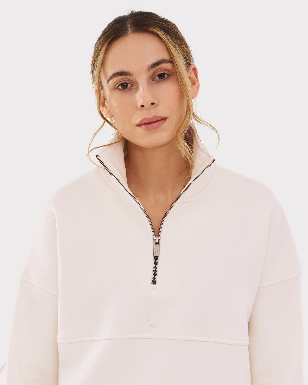 Frau trägt cremeweißen Half Zip Sweatshirt 'Cooper' mit hohem Kragen und halbem Reißverschluss
