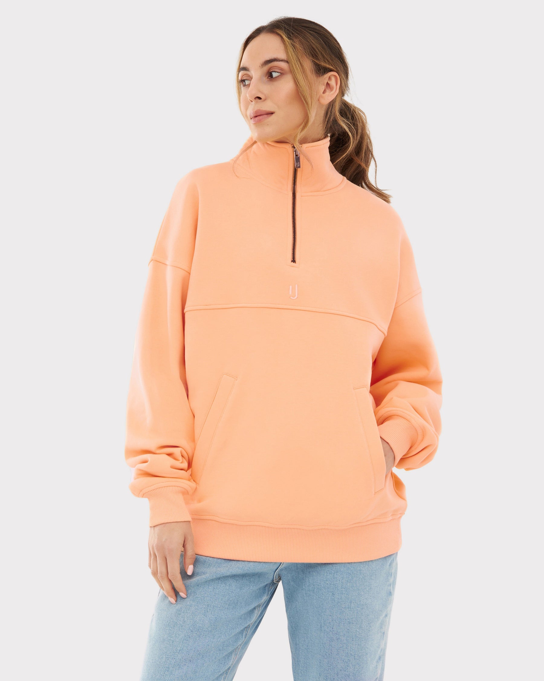 Damen trägt pfirsichfarbenen Half Zip Sweatshirt 'Cooper' mit halbem Reißverschluss und Kängurutasche