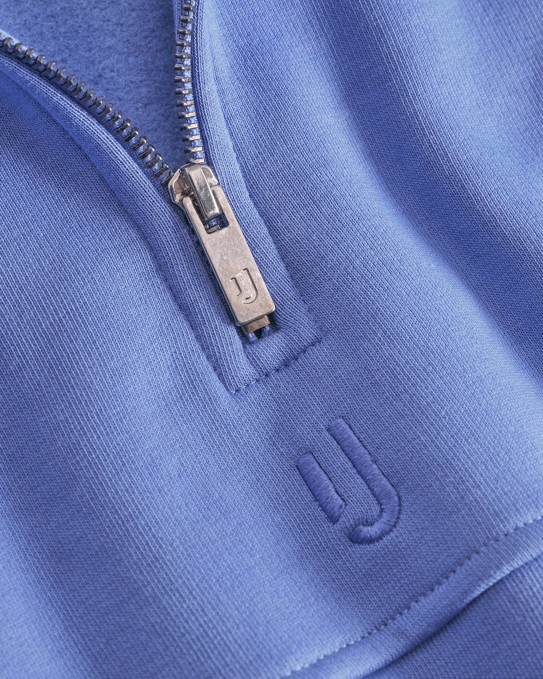 Nahaufnahme eines blauen Half-Zip-Sweatshirts 'Cooper' von Johnny Urban mit geprägtem Logo und silbernem Reißverschluss