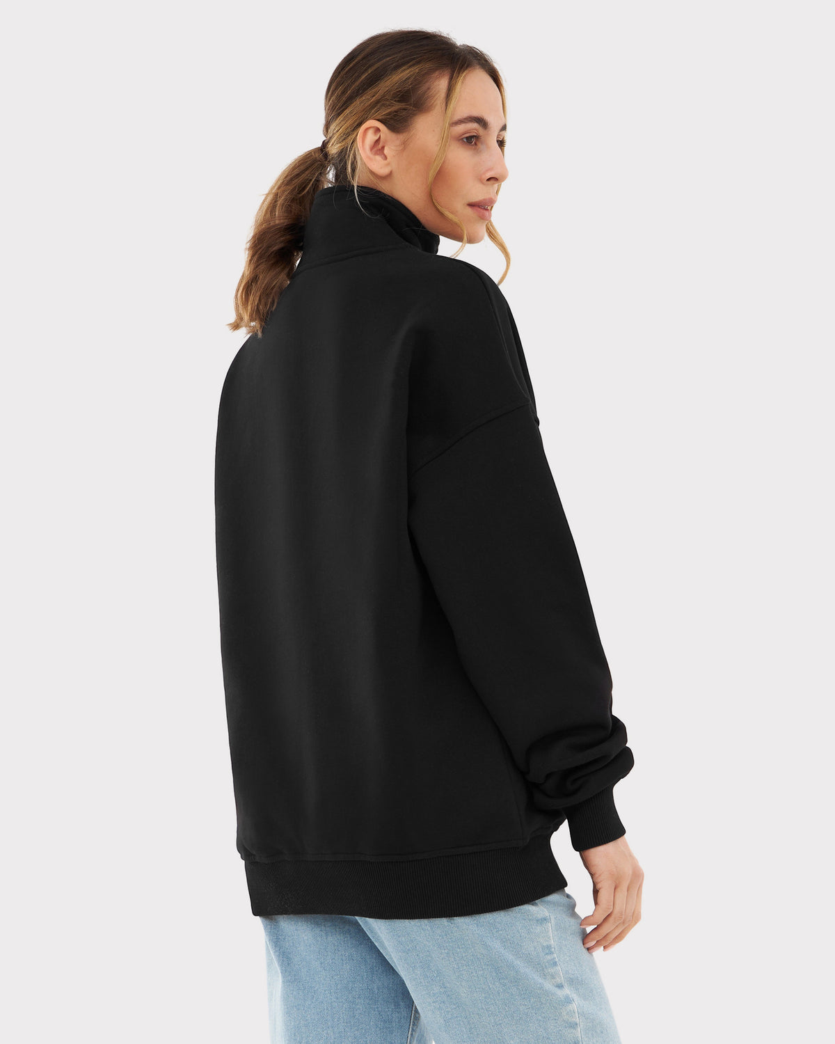 Frau mit halblangem Pferdeschwanz trägt schwarzen Oversize-Halbreißverschluss-Sweatshirt 'Cooper' von Johnny Urban