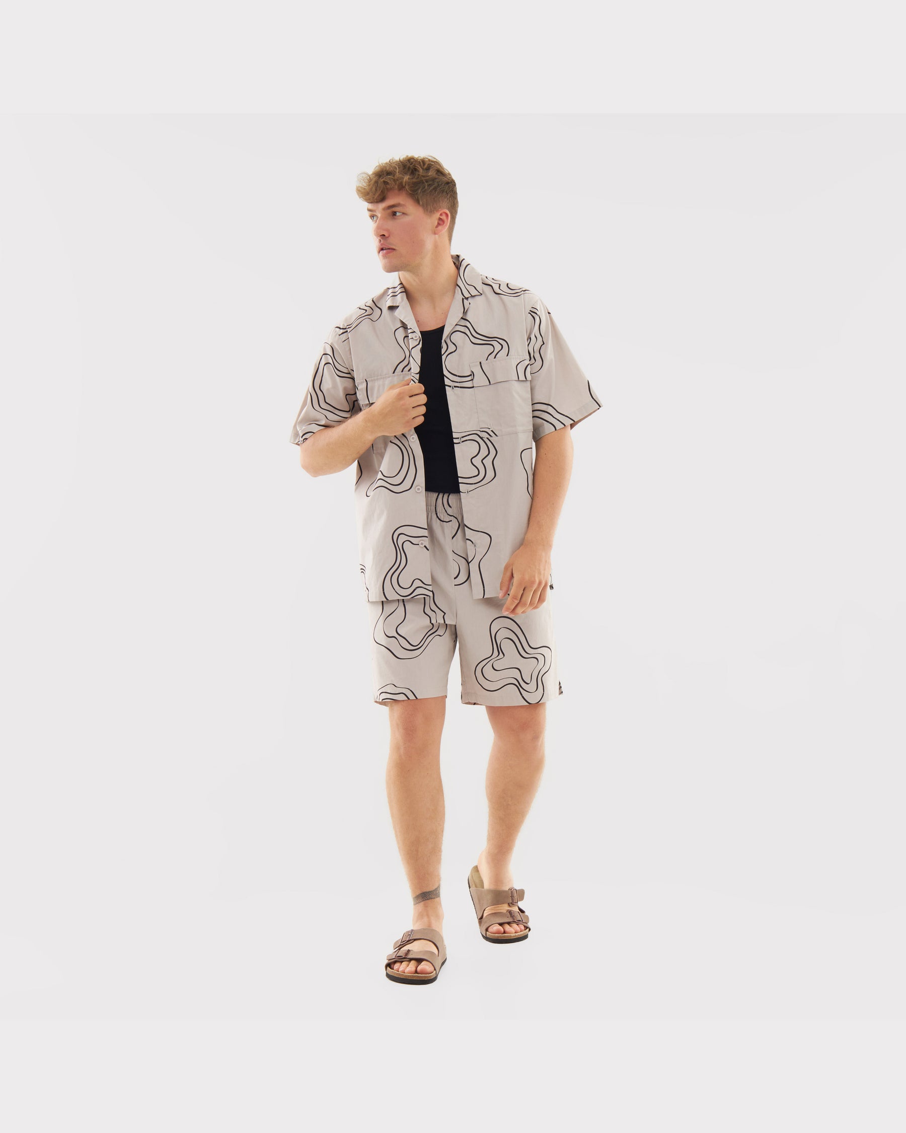 Mann trägt sandfarbenes Hemd und Shorts mit schwarzem abstraktem Muster aus Set 'Spencer'