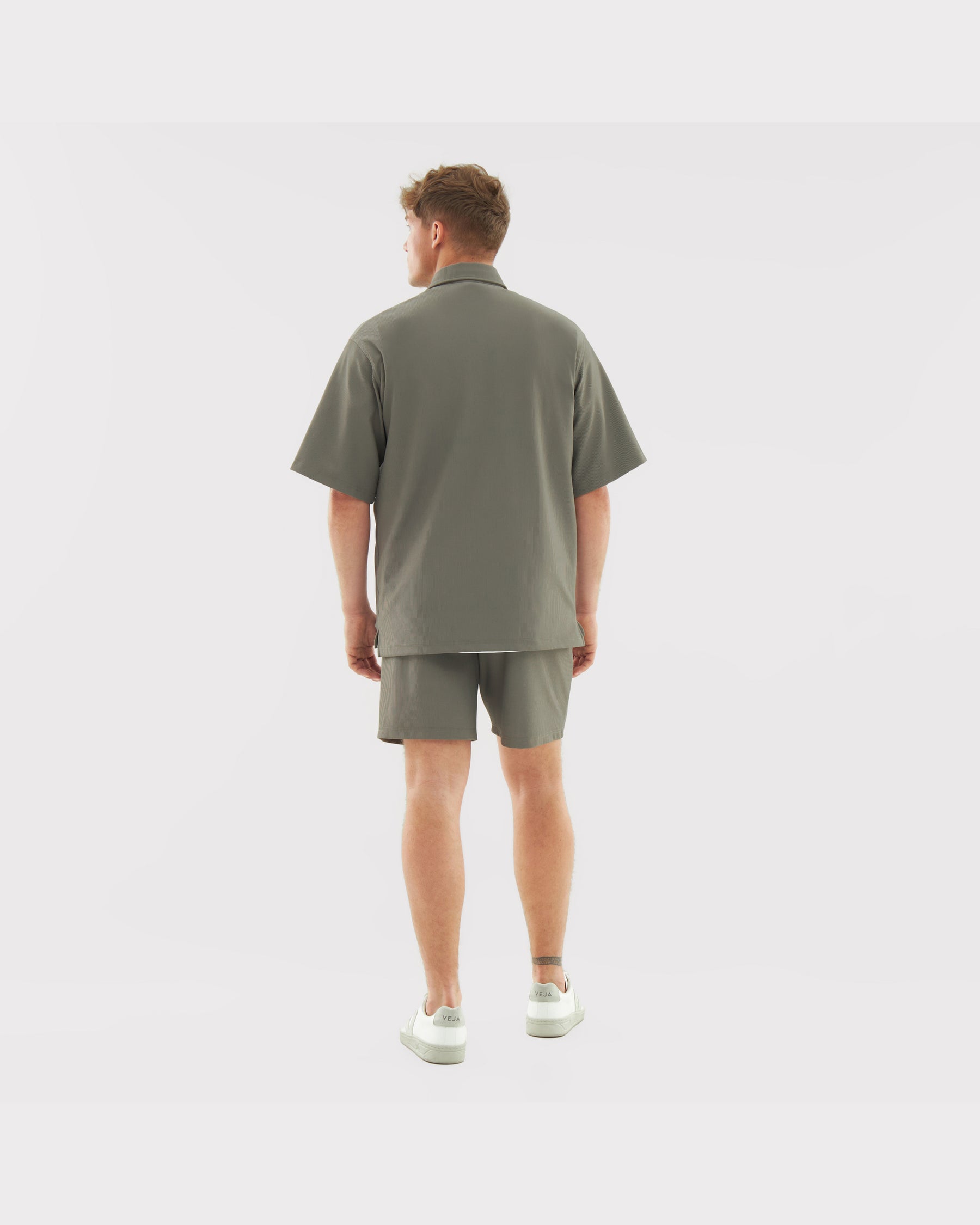 Männliches Modell trägt lockeres Oversize-Hemd und Shorts aus dem Set 'Mason' in grün, Rückansicht