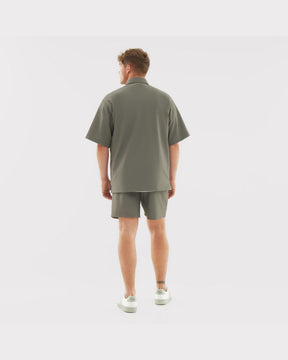 Männliches Modell trägt lockeres Oversize-Hemd und Shorts aus dem Set 'Mason' in grün, Rückansicht