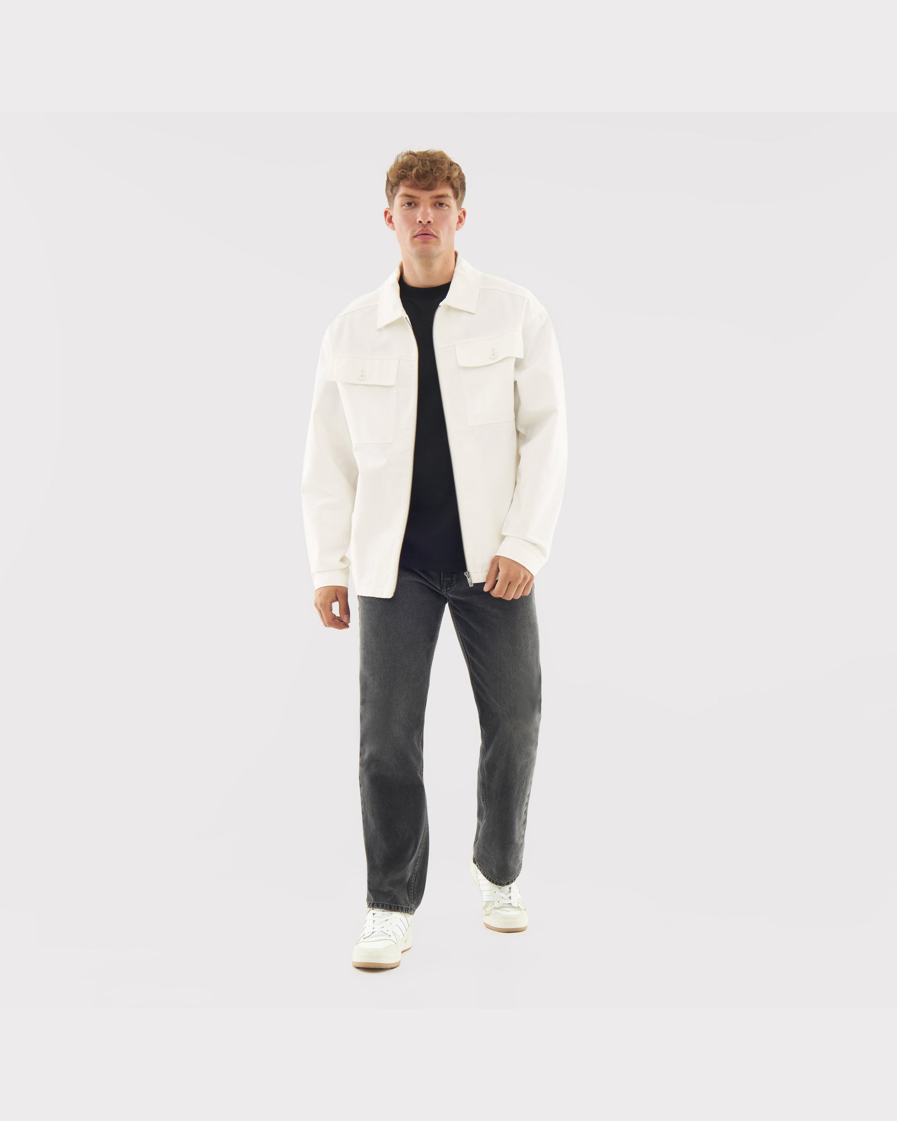 Mann trägt cremefarbene Overshirt 'Cameron' aus Baumwolle, kombiniert mit dunklen Jeans und weißen Schuhen