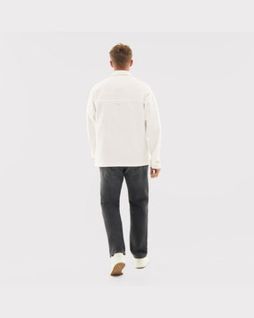 Rückansicht eines Mannes mit weißem Overshirt 'Cameron', dunkler Jeans und weißen Schuhen