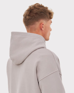 Rückansicht eines Mannes mit kurzem, lockigem Haar, der den oversized Hoodie 'Cody' in Grau trägt