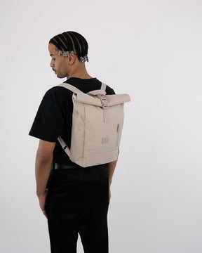 Mann trägt beigen Rolltop Rucksack 'Robin Small' von Johnny Urban, schwarze Kleidung