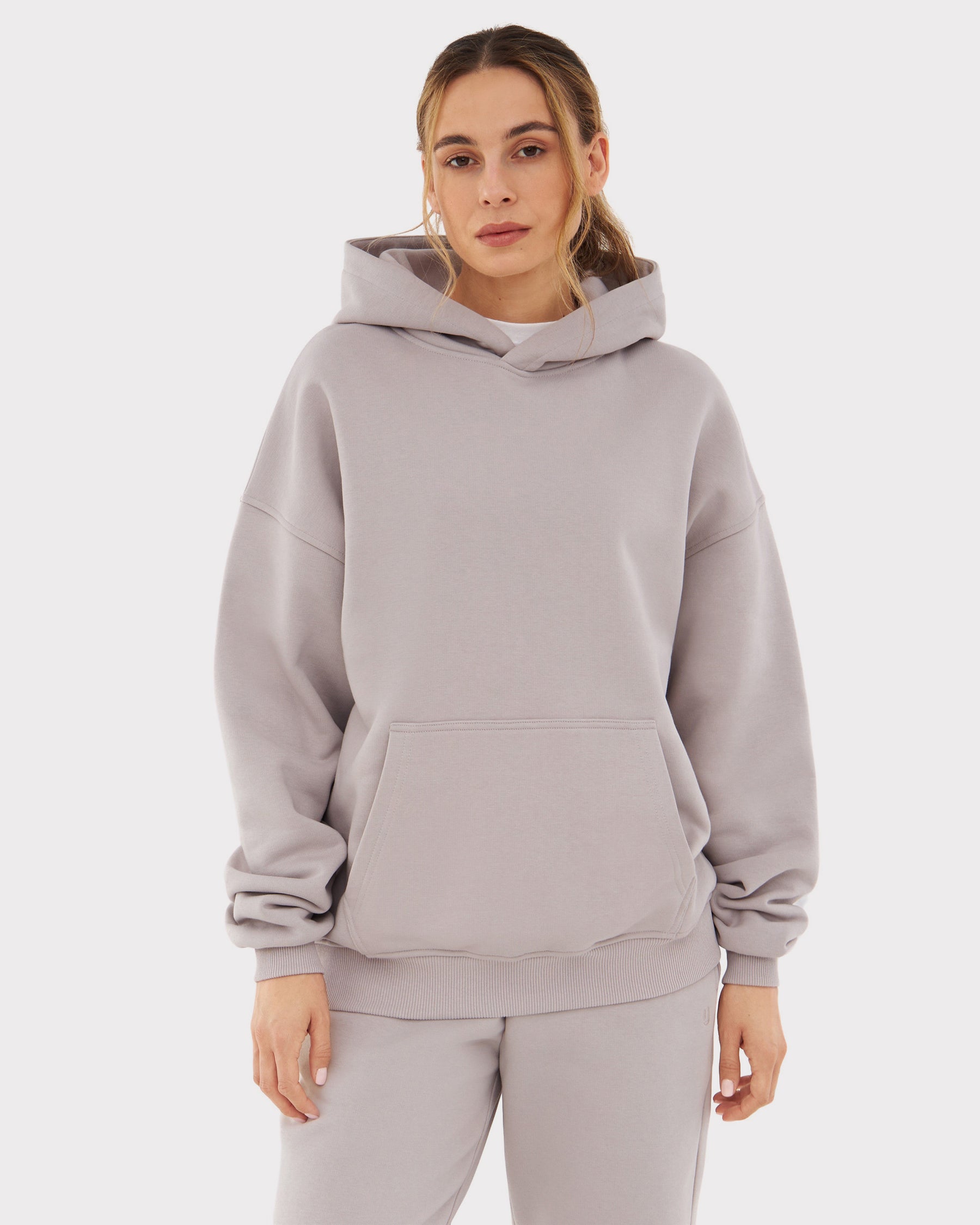 Übergroßer Hoodie 'Cody' in hellem Grau, getragen von Frau, mit Kapuze und Kängurutasche