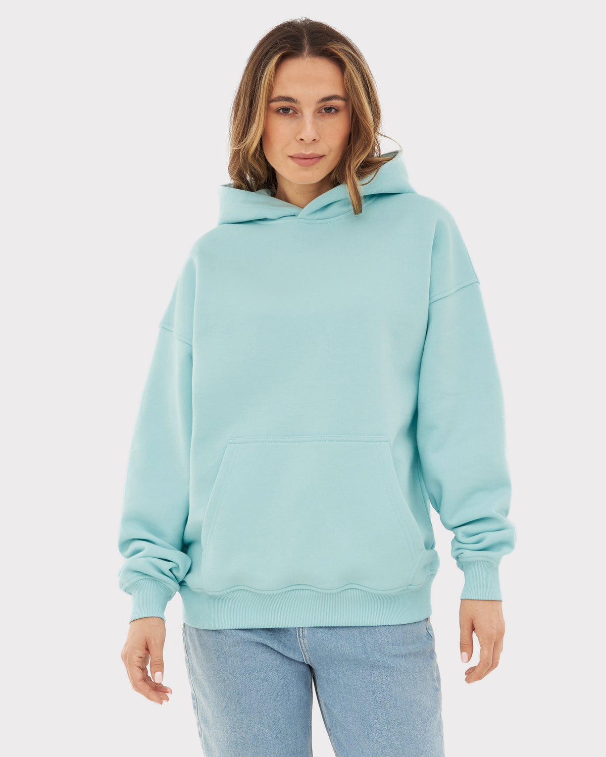 Frau trägt oversized Hoodie 'Cody' in eisblau mit Kängurutasche und Kapuze