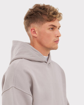 Mann trägt hellgrauen oversized Hoodie 'Cody' mit Kapuze, seitliche Ansicht