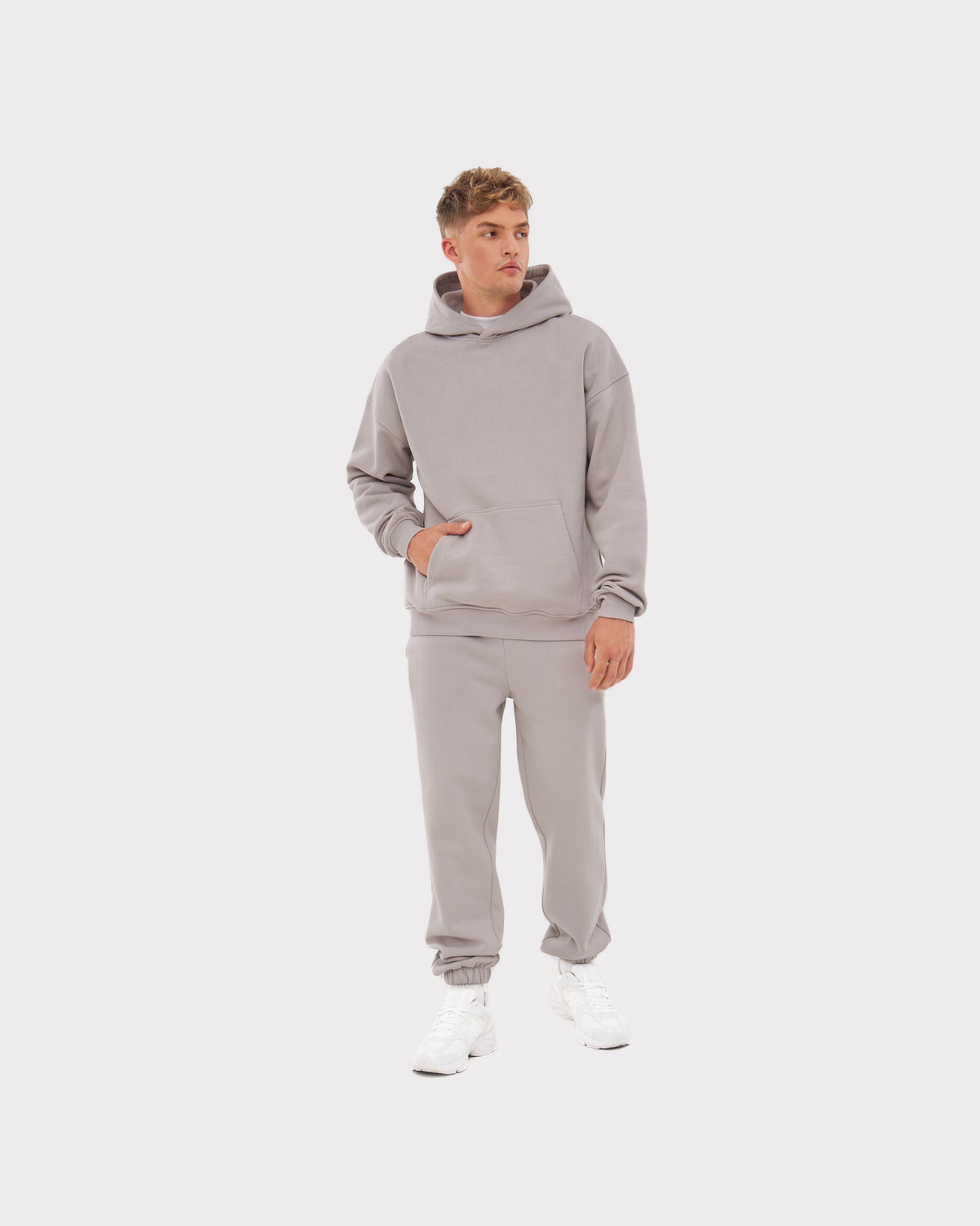 Mann trägt beige Oversized Hoodie 'Cody' und passende Jogginghose mit weißen Sneakers