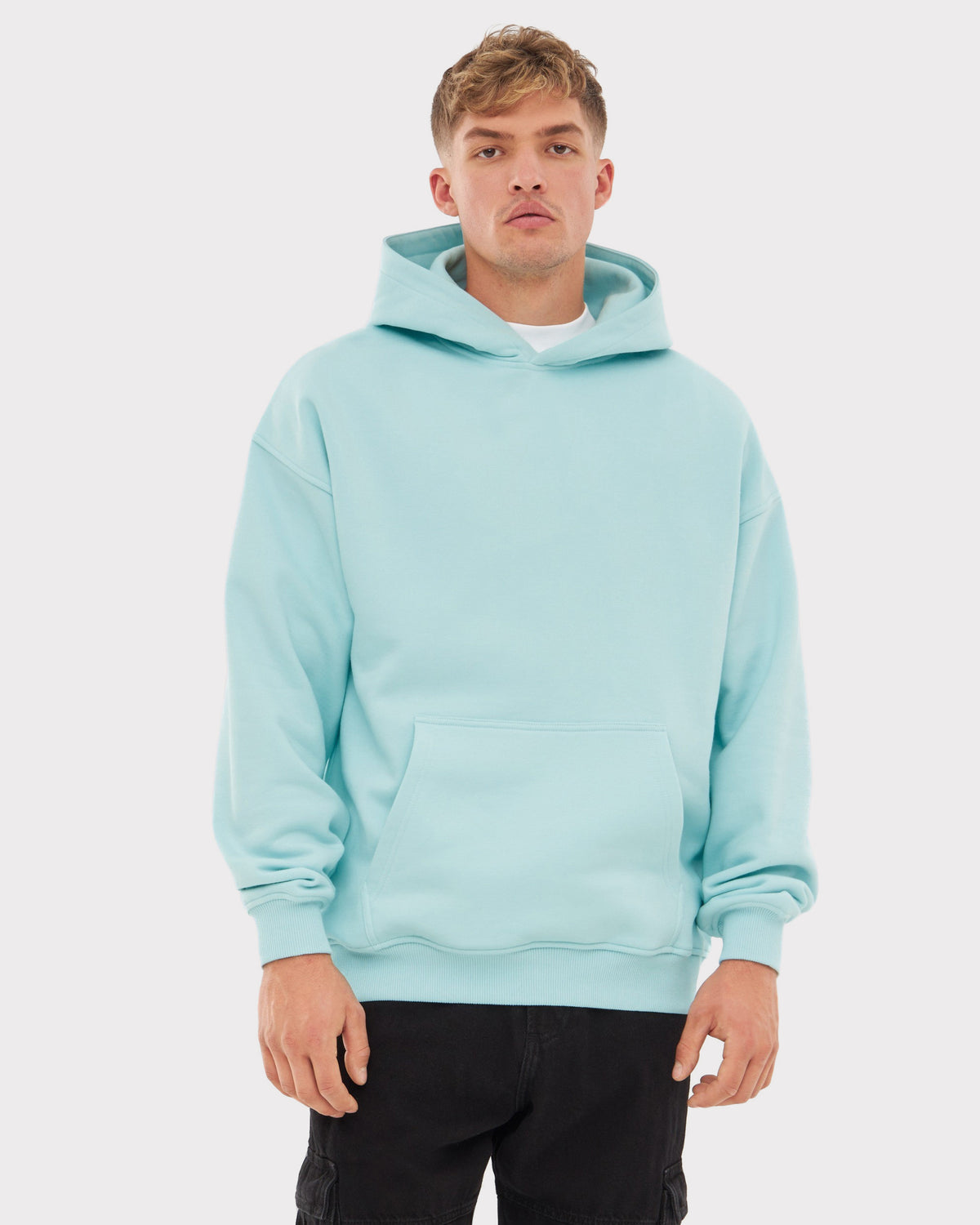 Mann trägt oversized Hoodie 'Cody' in eisblau mit Kängurutasche und Kapuze