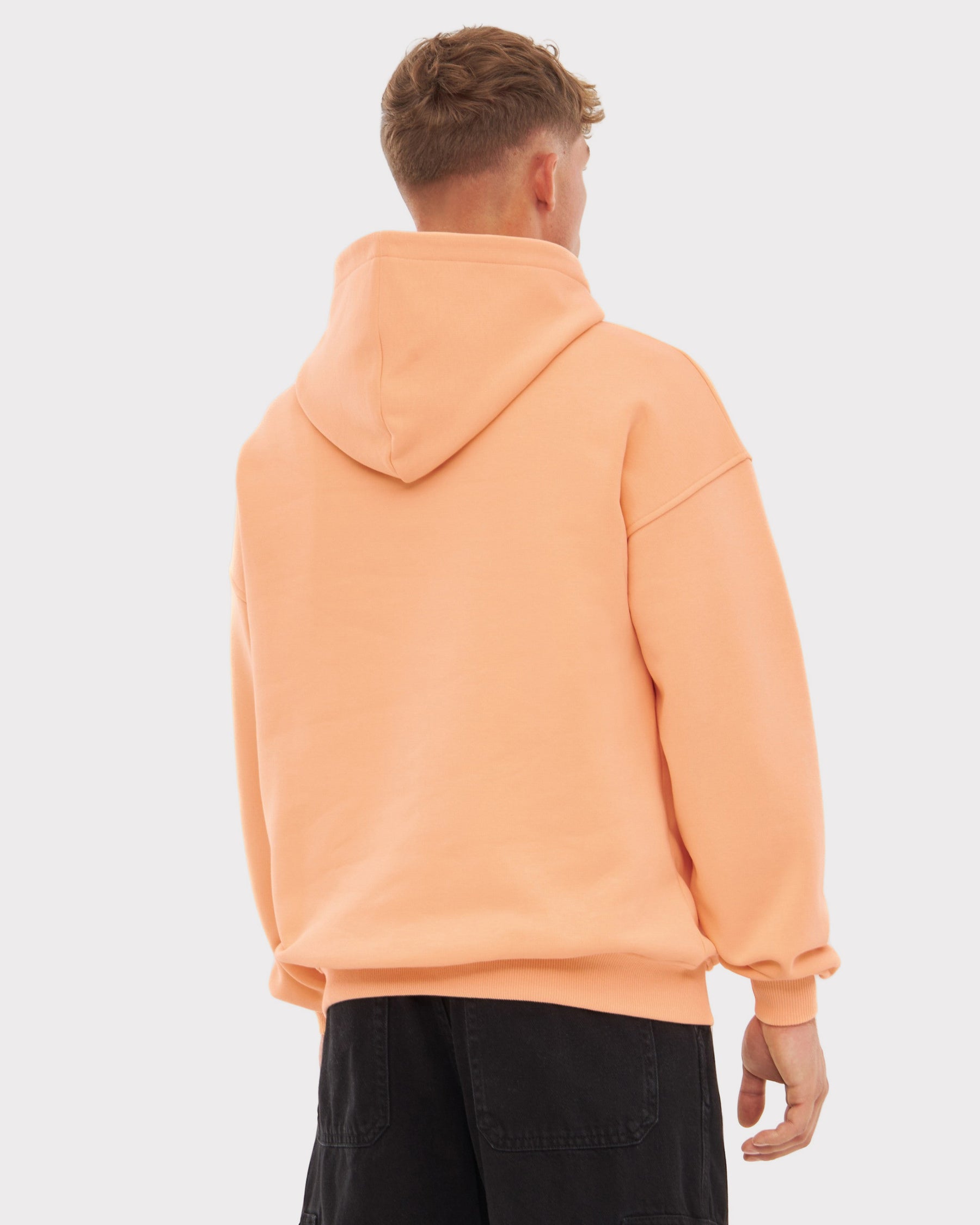 Mann trägt oversized Hoodie 'Cody' in Pfirsich, Ansicht von hinten