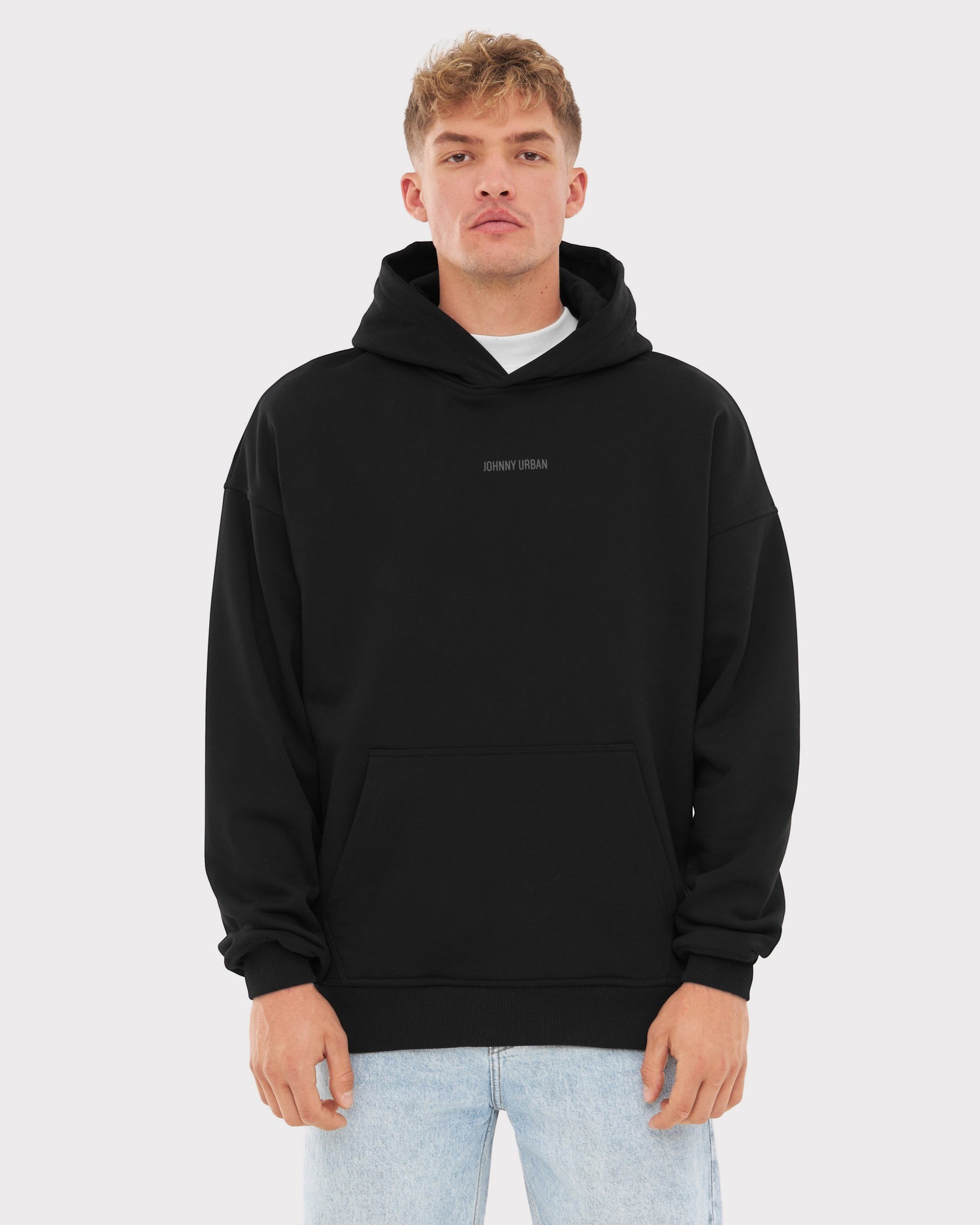 Mann trägt schwarzen oversized Hoodie 'Cody' mit Johnny Urban Print und heller Jeans