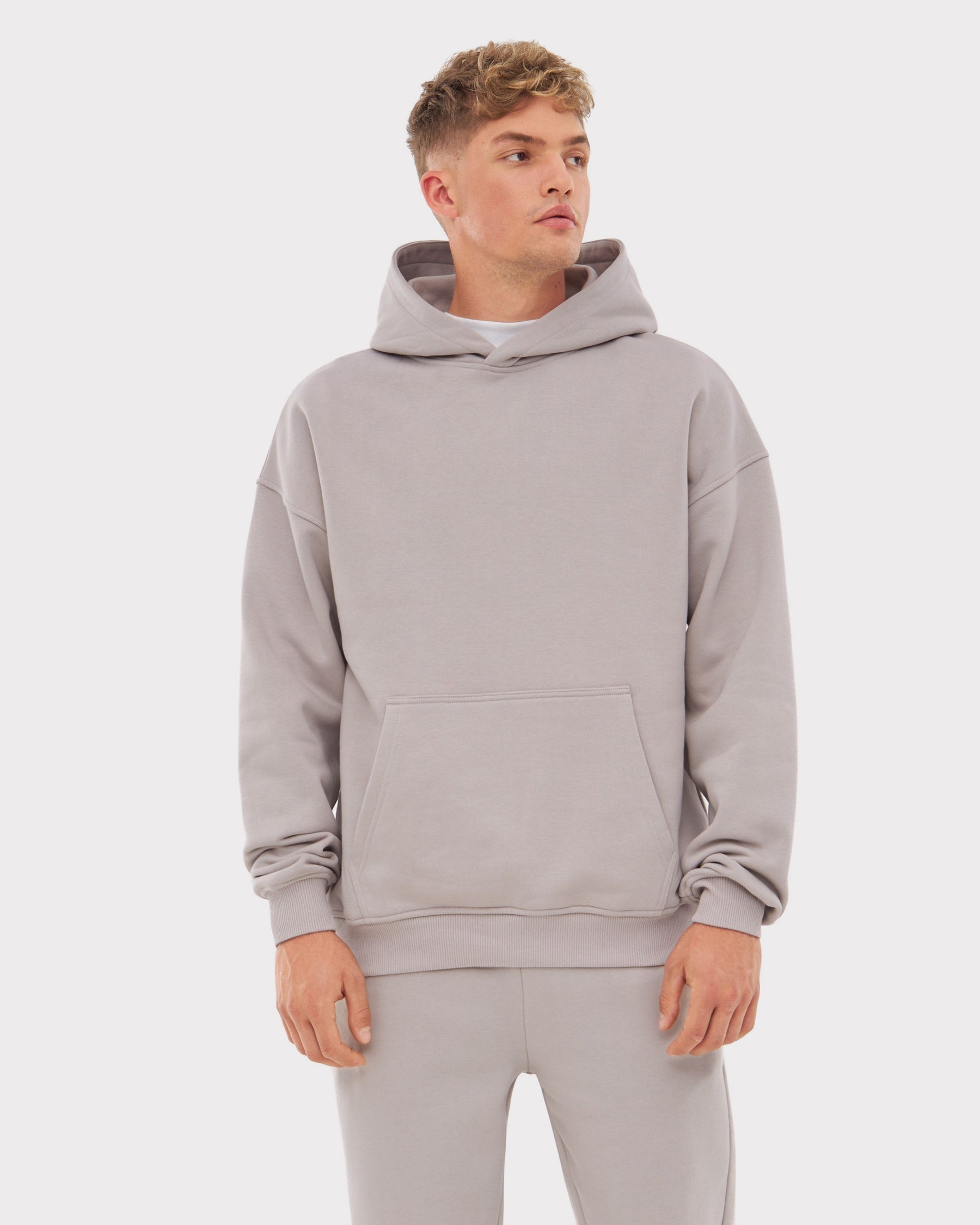 Mann trägt oversized Hoodie 'Cody' in Beige mit Kängurutasche und lockerem Sitz