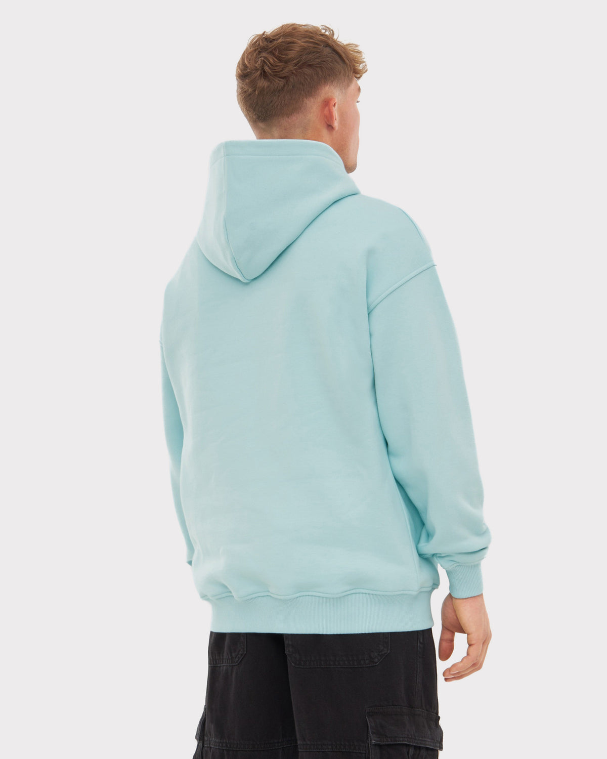 Mann trägt oversized Hoodie 'Cody' in hellblau, Rückansicht, schwarze Cargo-Shorts