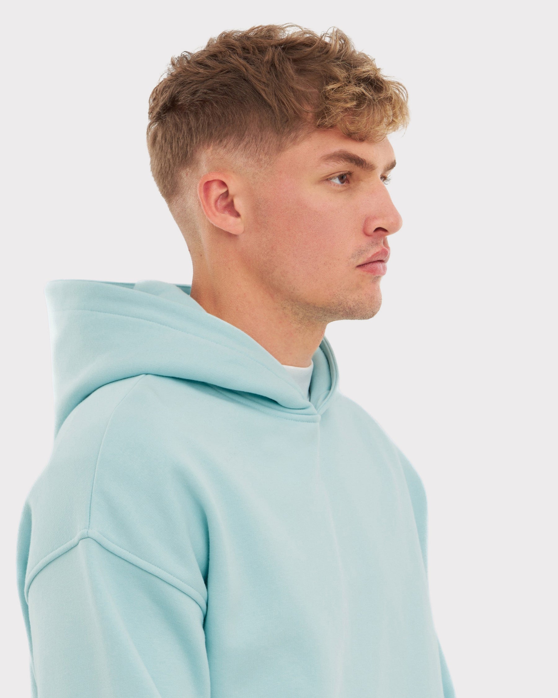 Mann trägt oversized Hoodie 'Cody' in eisblau, Seitenansicht