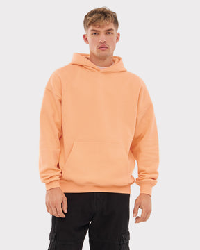 Mann trägt oversized Hoodie 'Cody' in Pfirsich mit Kapuze und Kängurutasche