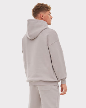 Mann trägt oversized Hoodie 'Cody' in warmem Grau, Ansicht von hinten