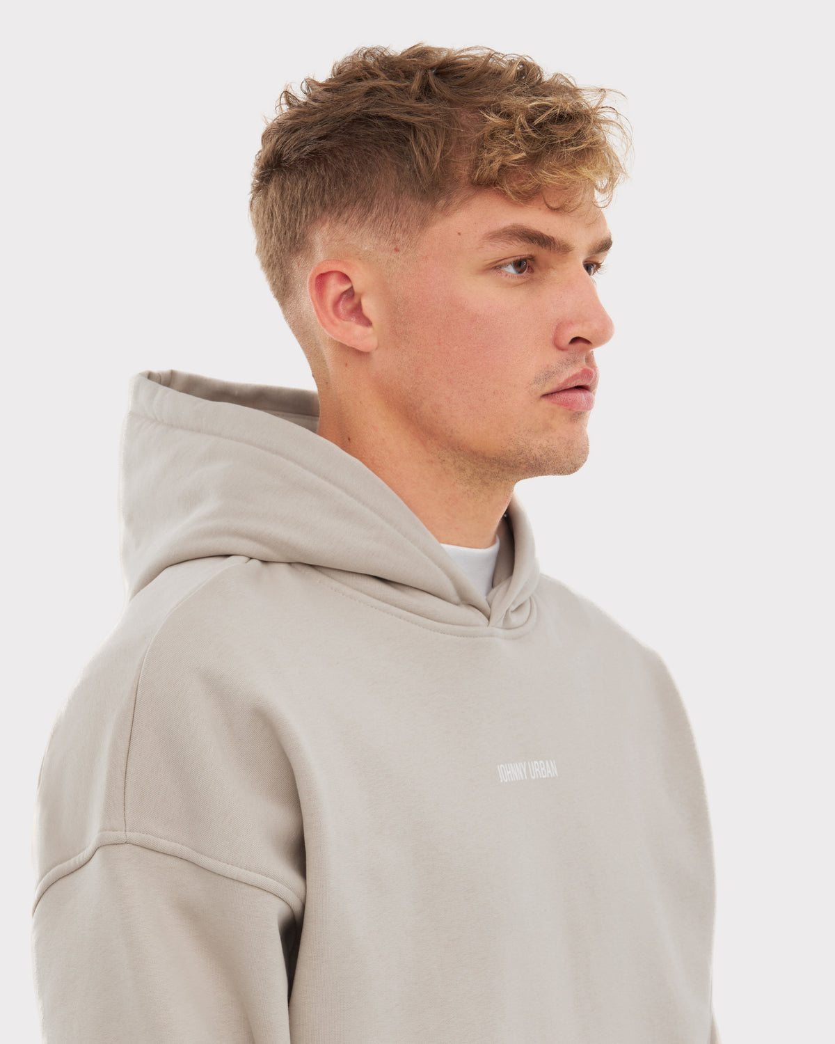 Mann trägt übergroßen beigen Hoodie 'Cody' von Johnny Urban mit kleinem Logo auf der Brust