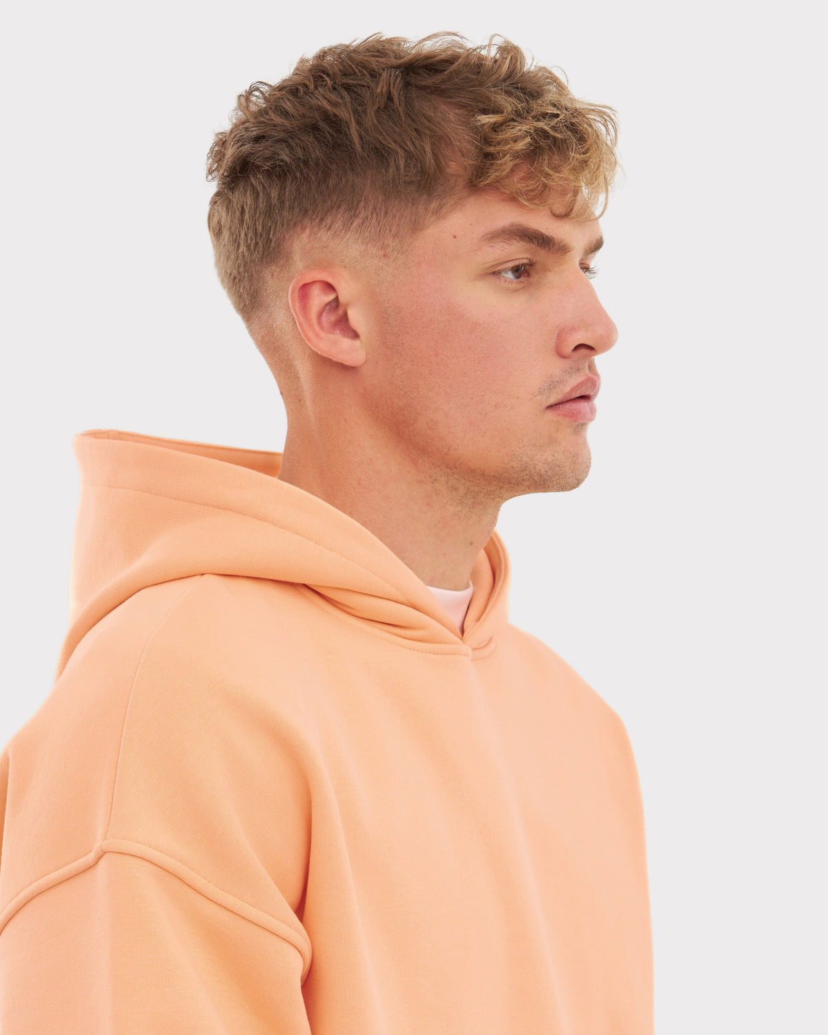 Mann im Profil trägt oversized Hoodie 'Cody' in Pfirsichfarbe mit Kapuze