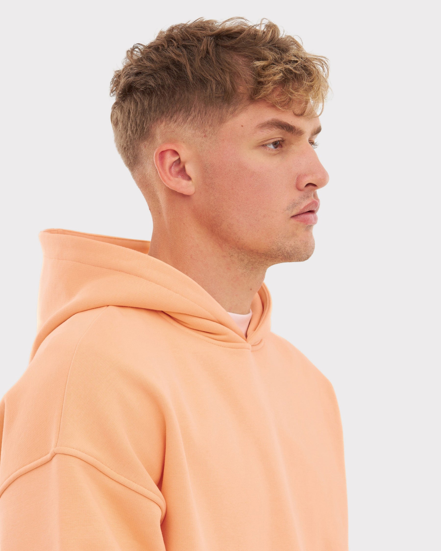 Mann im Profil trägt oversized Hoodie 'Cody' in Pfirsichfarbe mit Kapuze