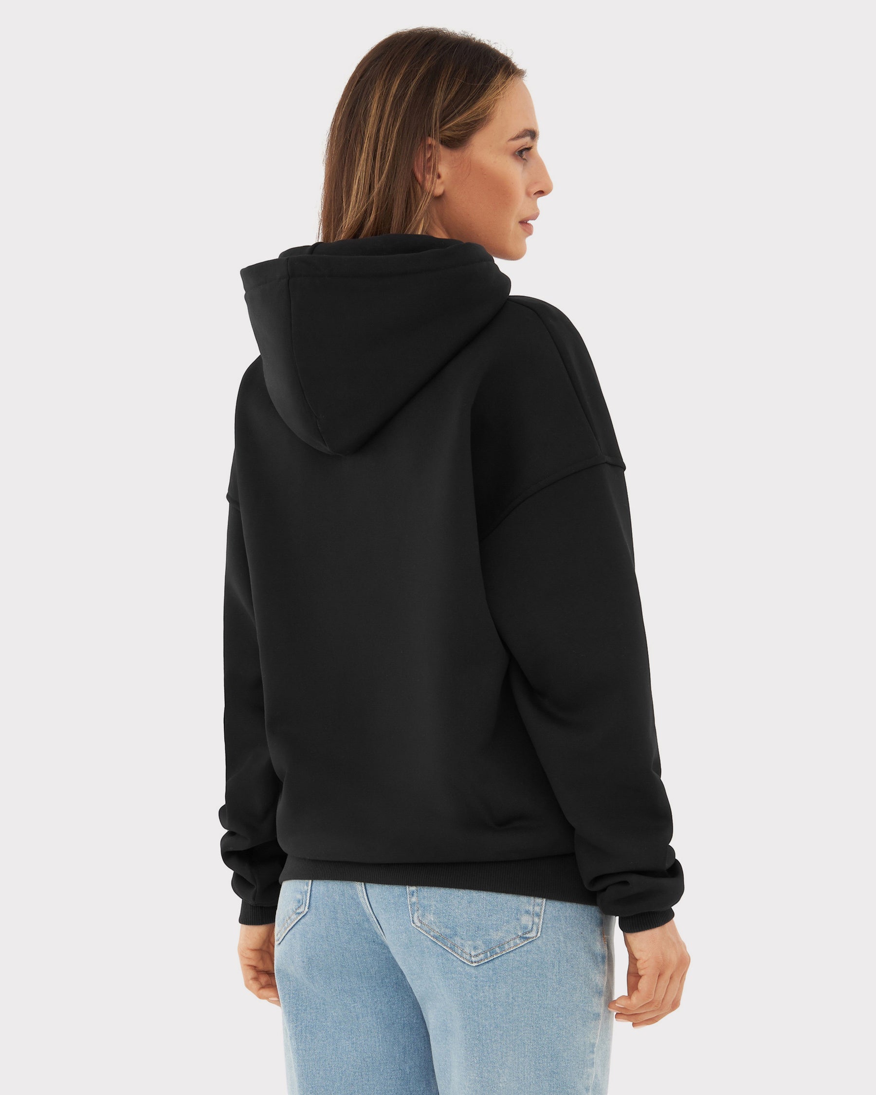 Rückansicht eines jungen Frau mit oversized Hoodie 'Cody' in Schwarz und hellblauer Jeans