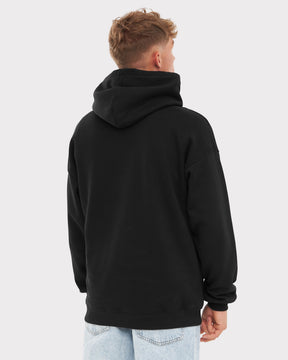 Mann trägt schwarzen Oversized Hoodie 'Cody' von hinten, dazu helle Jeans