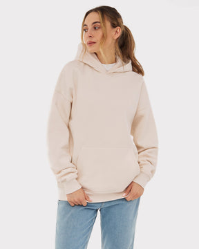 Frau trägt oversized Hoodie 'Cody' in Beige mit Kapuze und Kängurutasche, kombiniert mit blauen Jeans