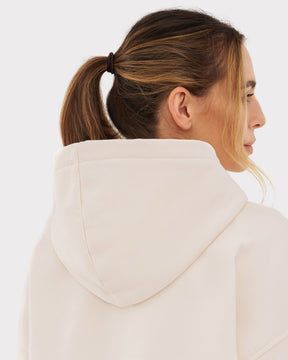 Frau mit zusammengebundenem Haar trägt oversized Hoodie 'Cody' in hellem Beige, Rückansicht mit Kapuze