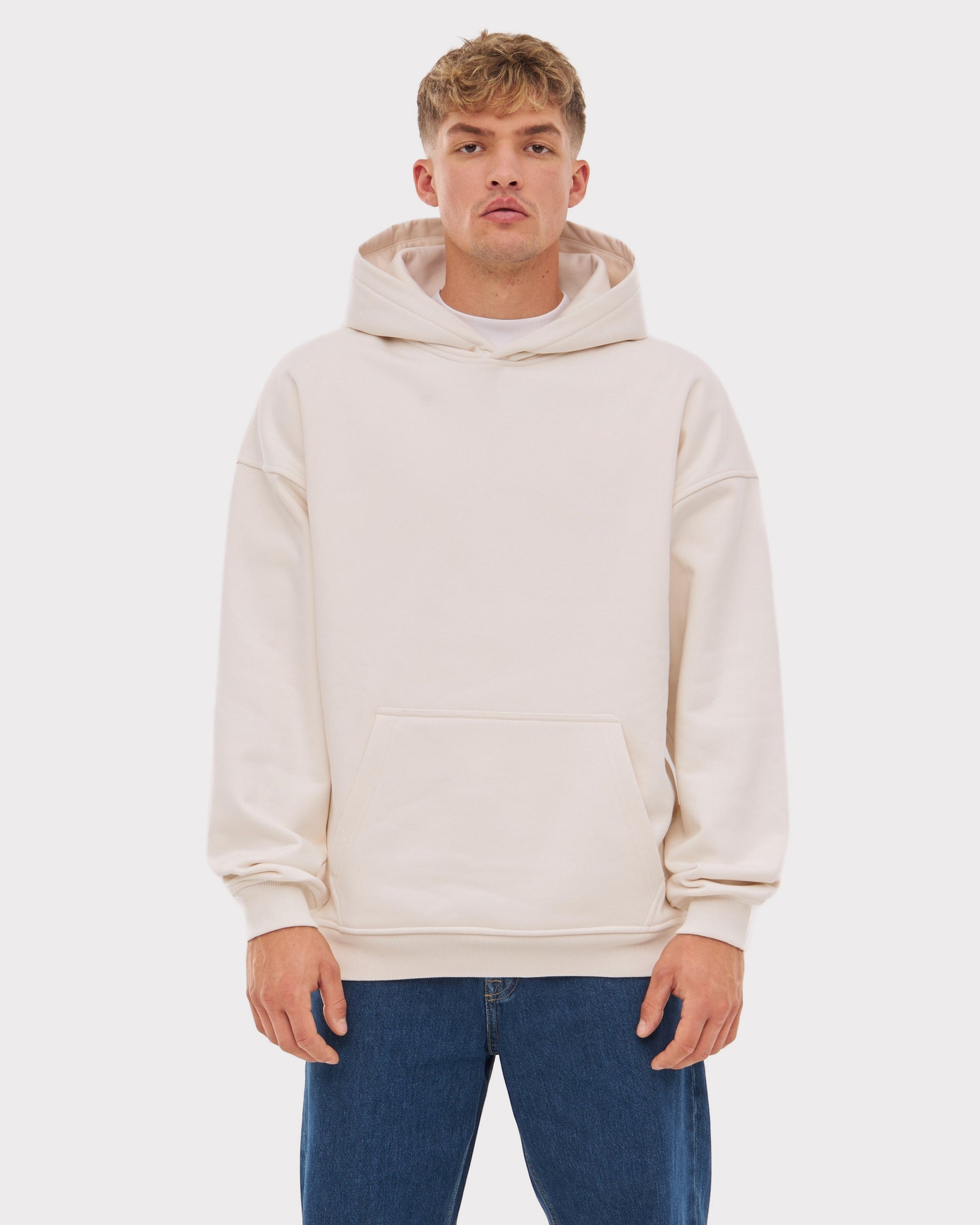 Mann trägt beigen Oversized Hoodie 'Cody' mit Kängurutasche und Kapuze