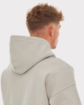 Mann mit kurzem blondem Haar trägt einen oversized Hoodie 'Cody' in hellem Beige mit Kapuze