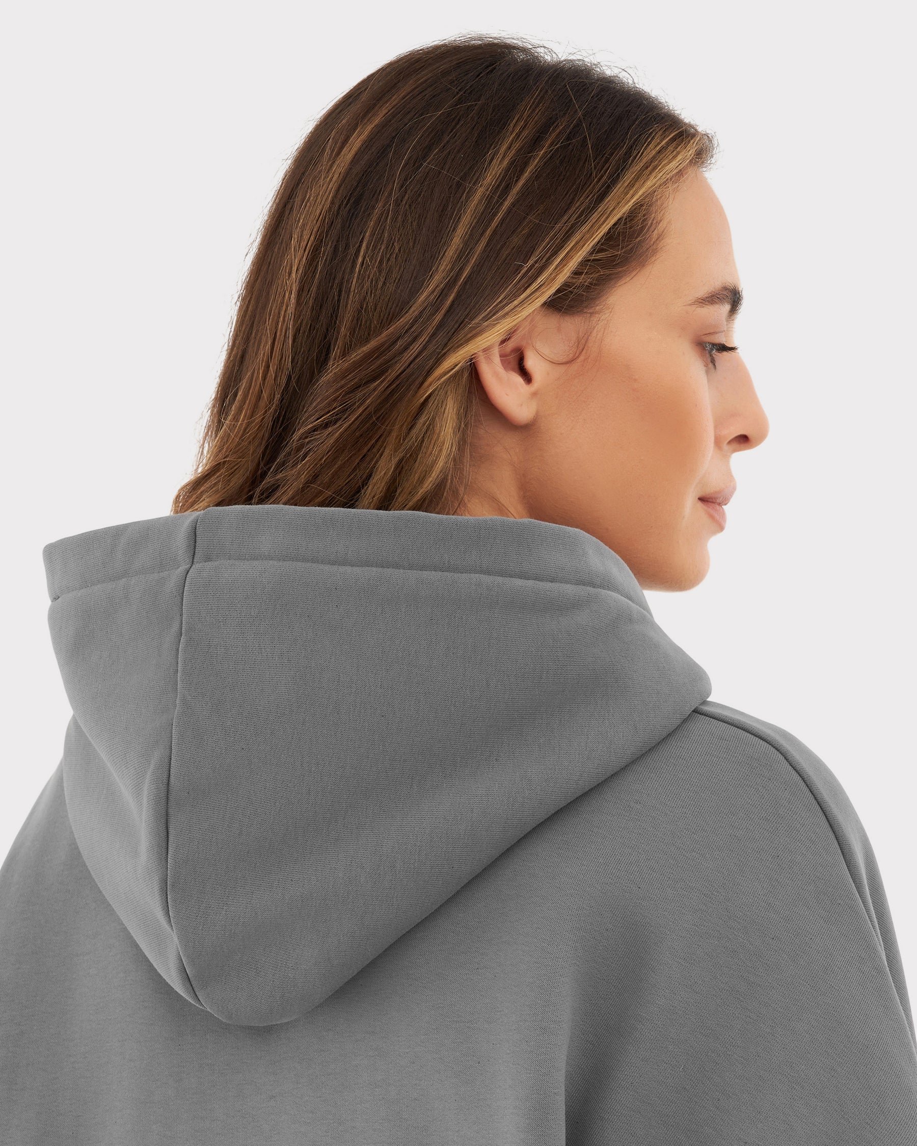 Frau mit hellbraunen Haaren von hinten in grauem, oversized Hoodie 'Cody' mit Kapuze