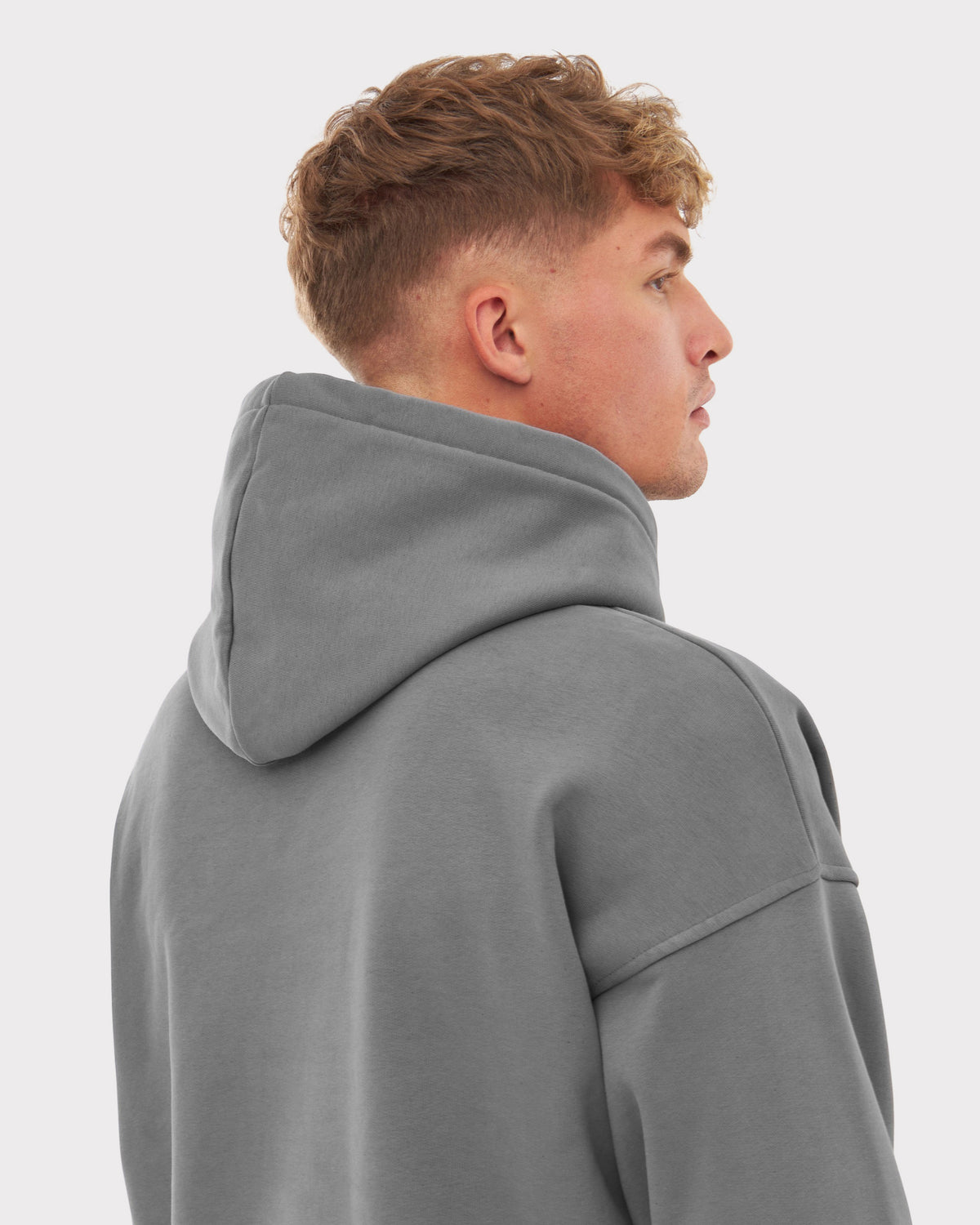 Männliches Modell von hinten mit oversized Hoodie 'Cody' in Grau, Kapuze hochgeklappt
