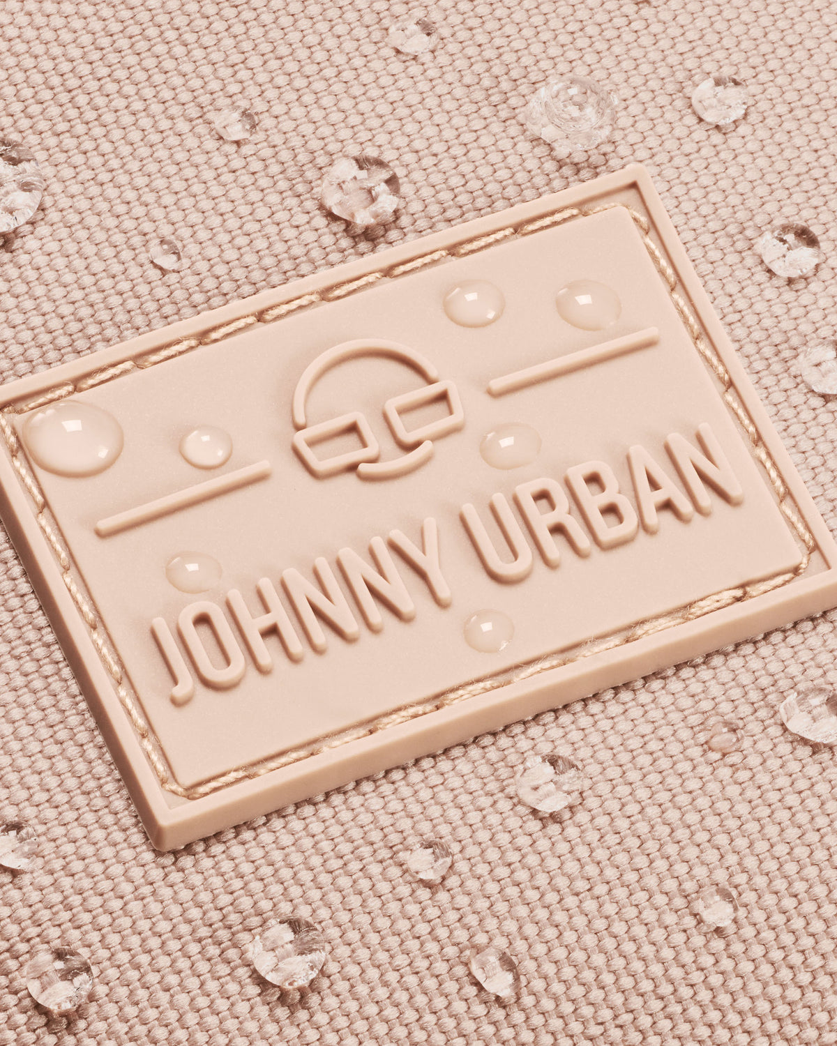 Nahaufnahme des Johnny Urban Logos auf der rosafarbenen Bauchtasche Erik Large mit Wasserperlen