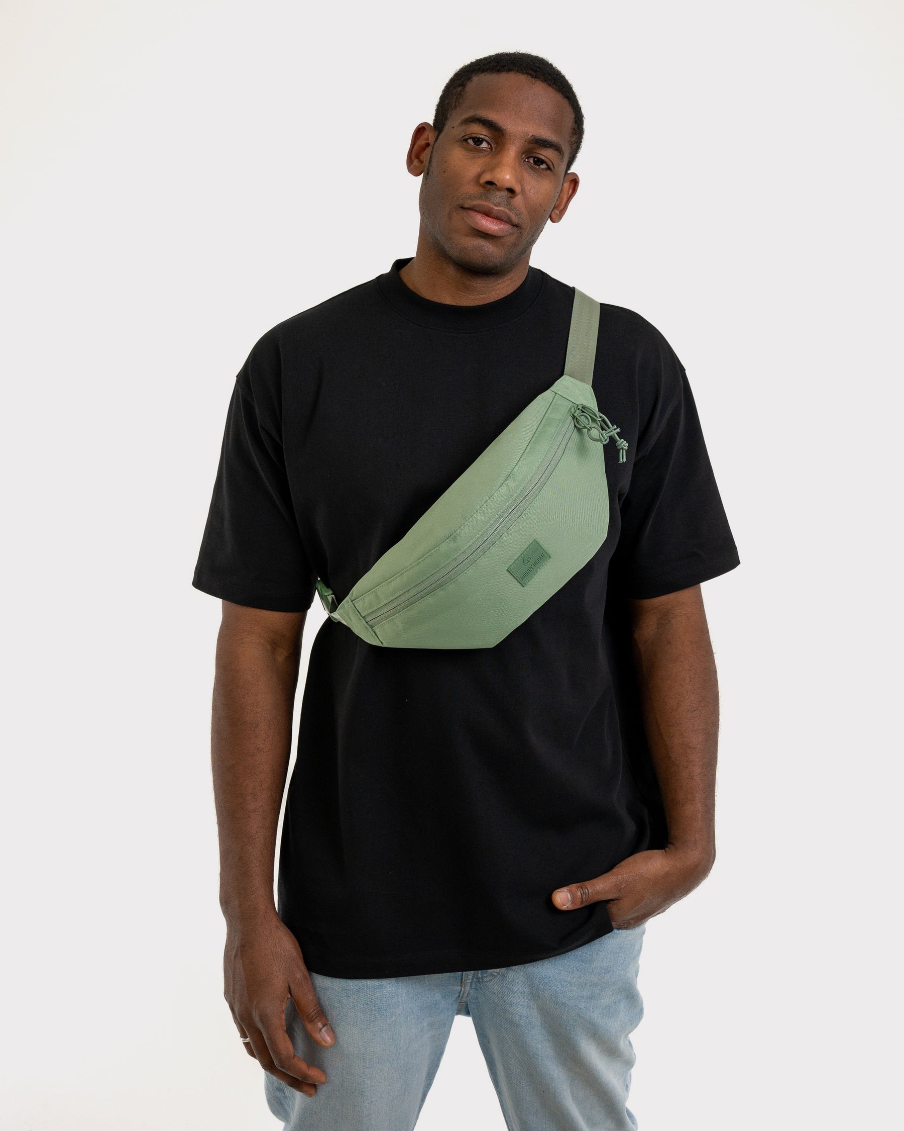 Mann trägt sagegrüne Bauchtasche 'Erik Large' von Johnny Urban über schwarzem T-Shirt