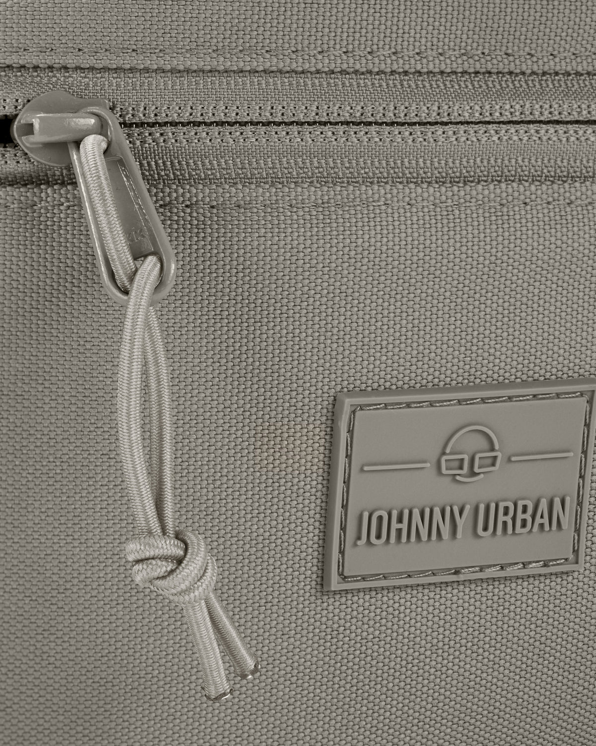 Detailansicht eines Reißverschlusses und des Johnny Urban Logos auf der Bauchtasche 'Erik Large' in desert grey