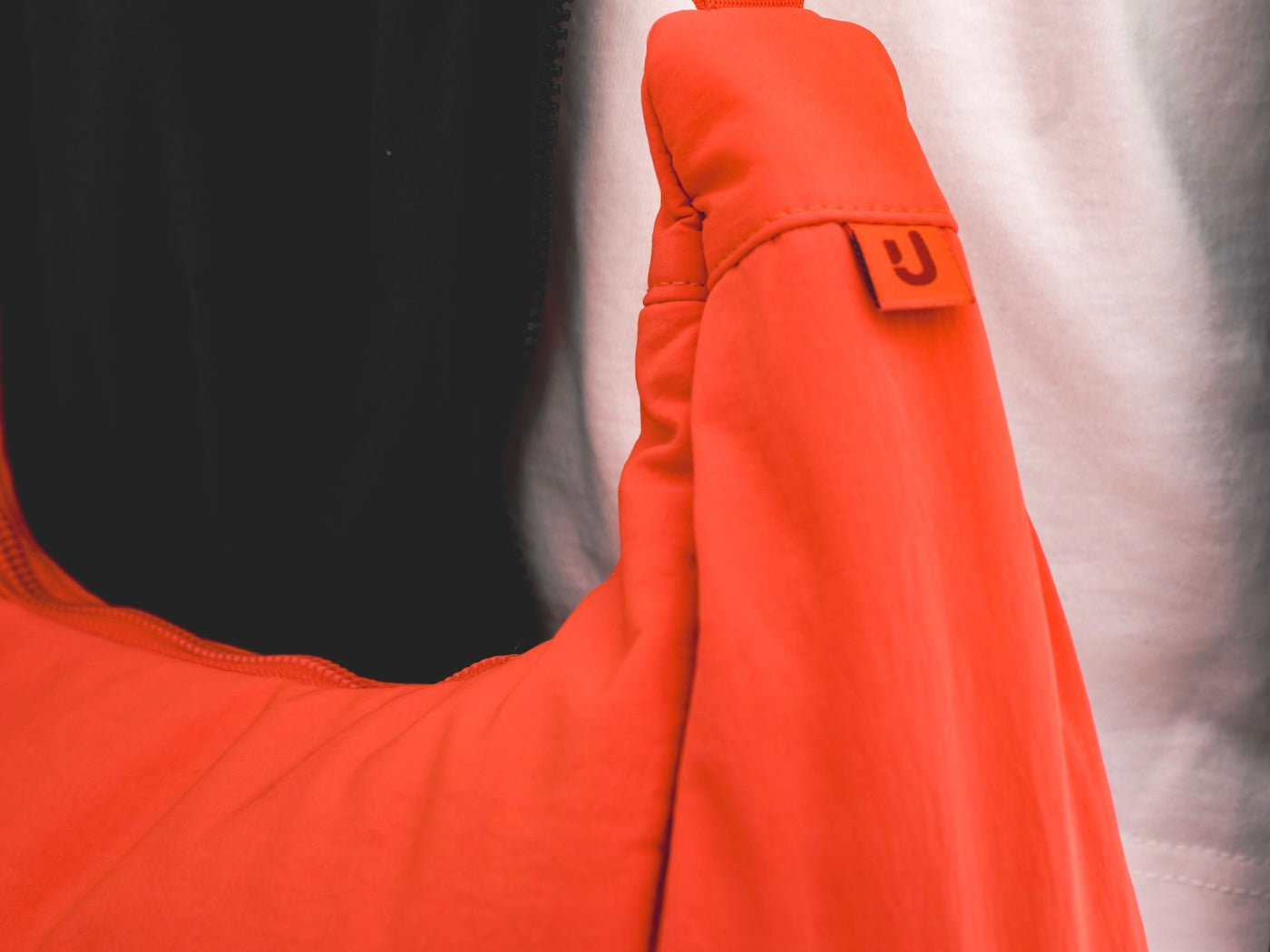 EIn Closeup unseres Johnny Urban Logos auf dieser coral-roten Half-Moon-Bag "Lou Medium". 