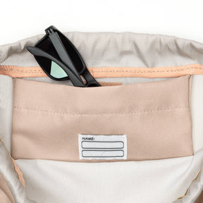 Innenfach des Kinder Turnbeutels 'Nino' mit beige Stoff und Namensfeld, schwarze Sonnenbrille steckt im Fach