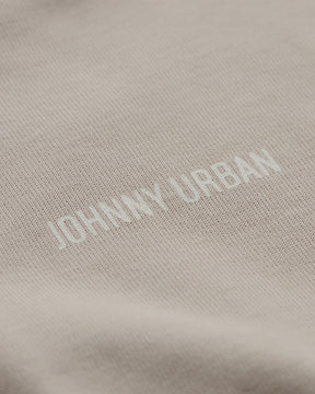 Detailaufnahme eines beigen T-Shirts mit geprägtem 'Johnny Urban' Schriftzug