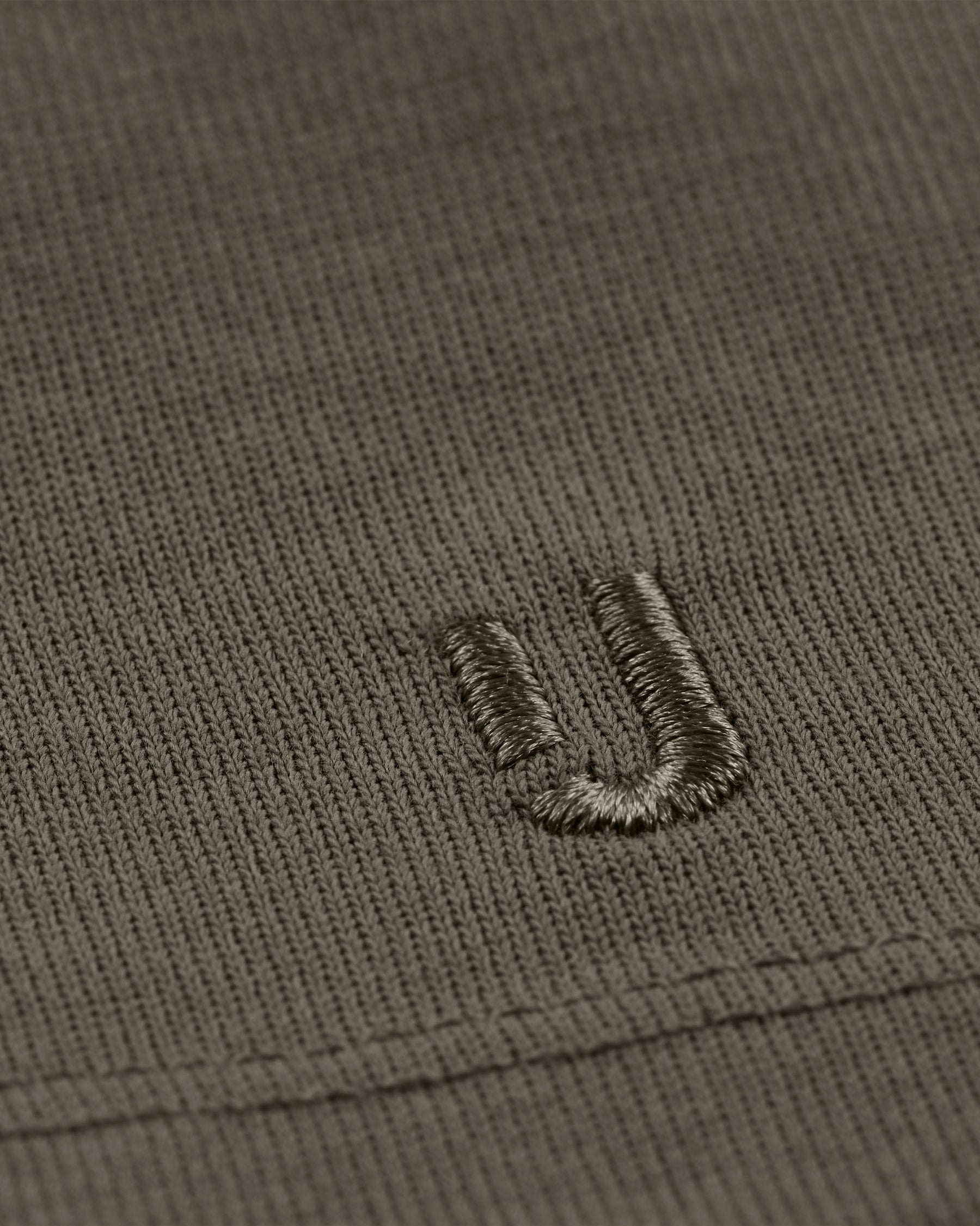 Nahaufnahme des grauen Stoffes mit gesticktem Johnny Urban Logo