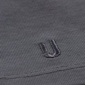 Nahaufnahme des grauen Baumwollstoffs eines T-Shirts mit eingesticktem 'ju'-Logo