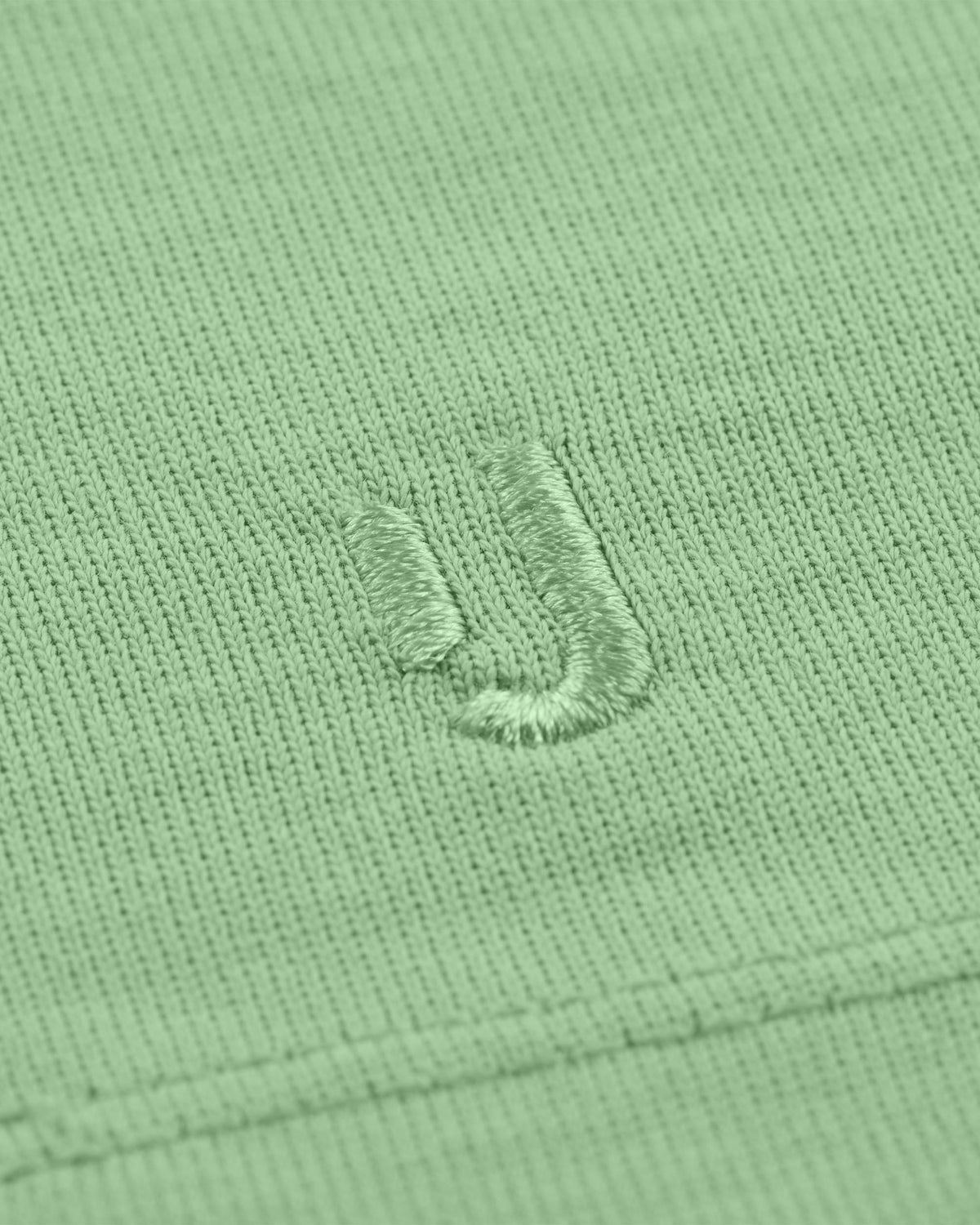 Nahaufnahme des gestickten Johnny Urban Logos auf dem T-Shirt 'Sammy' in Salbeigrün